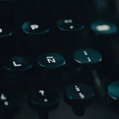 Klawiatura maszyny do pisania, z widocznymi literami i cyframi. Może to być tło dla historii o pomyłkach freudowskich, gdzie przypadkowe naciśnięcie klawisza ujawnia ukryte myśli.
