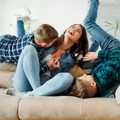 Szczęśliwa matka śmieje się, gdy jej synowie wspinają się na nią jak na partnera do zabawy.