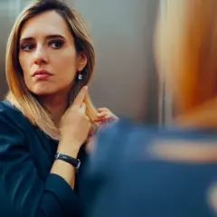 Kobieta w granatowej marynarce poprawia włosy, zastanawiając się, po jakim czasie narcyz wraca.