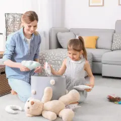 Mama i córka sprzątają zabawki. Dziecko uczy się obowiązków w domu, jakby obowiązywała ustawa o porządku.