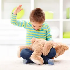 Chłopiec ćwiczy trening zastępowania agresji, przytulając misia.