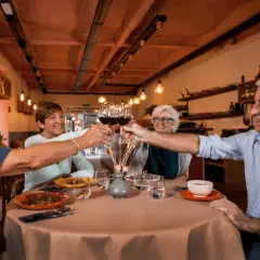 Cztery osoby wznoszą toast kieliszkami wina, tworząc radosny efekt cocktail party.