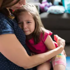 Smutna dziewczynka mocno przytula się do mamy. Widać jej łzy, co może świadczyć o lęku separacyjnym u 8 latka.