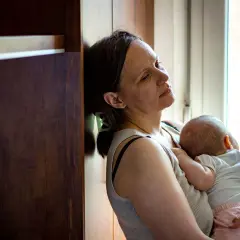 Zmęczona kobieta tuli śpiące dziecko. Czasem mam dość swojego dziecka, ale miłość jest silniejsza.