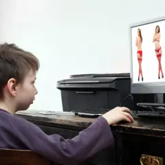 Chłopiec patrzy na ekran komputera, na którym wyświetlone są zdjęcia kobiet w bieliźnie.