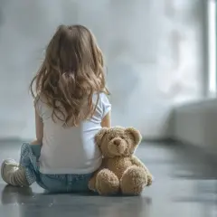 Dziewczynka z misiem, jej świat jest inny. Autyzm u dziewczynek bywa trudny do zauważenia.