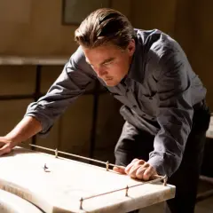 Leonardo DiCaprio pochyla się nad stołem, obserwując wirujący bączek. Czy to jego sposób na zrozumienie, czym jest incepcja?