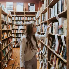 Studentka w księgarni przegląda półki z książkami, szukając inspiracji do swoich studiów z historii sztuki.