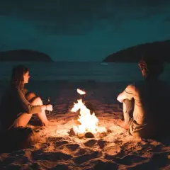 Para siedzi przy ognisku na plaży. Ona trzyma butelkę, on patrzy w dal. Czy on czuje, że nie umiem kochać?