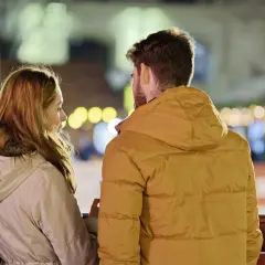Para rozmawia, ciesząc się wieczorem. Ich przyjaźń damsko męska kwitnie w blasku świateł.