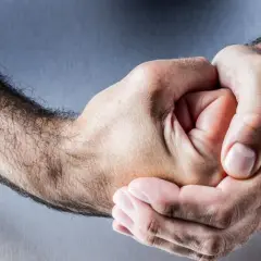 Dłonie splatają się w uścisku, sugerując napięcie lub niechęć, jakby ktoś był uprzedzony do mężczyzn.