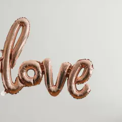 Różowe balony w kształcie napisu "love" unoszą się w powietrzu, tworząc piękną definicję miłości.
