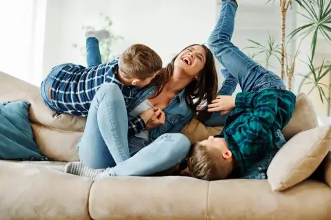 Szczęśliwa matka śmieje się, gdy jej synowie wspinają się na nią jak na partnera do zabawy.