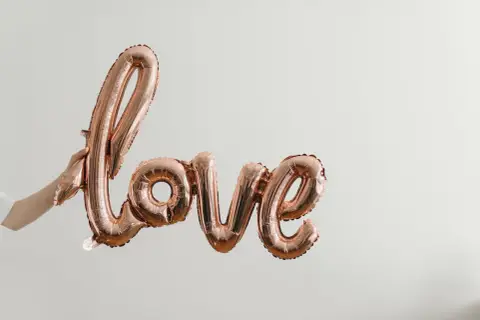 Różowe balony w kształcie napisu "love" unoszą się w powietrzu, tworząc piękną definicję miłości.
