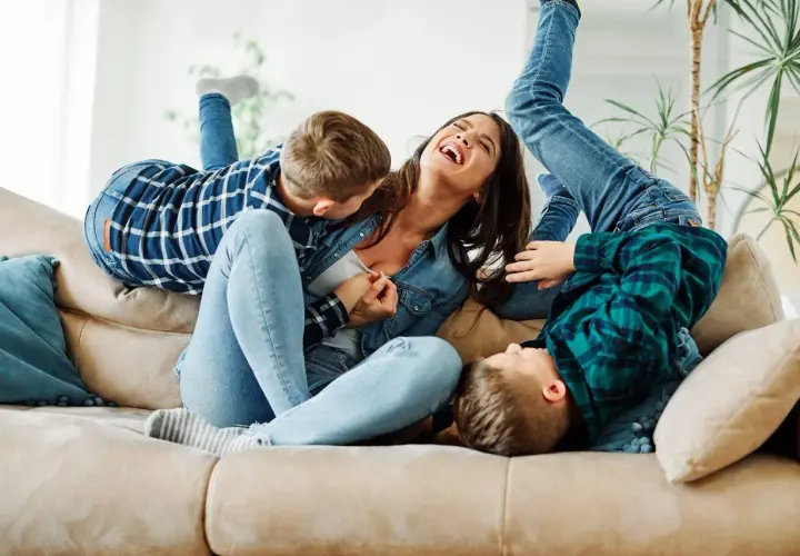 Szczęśliwa matka śmieje się, gdy jej synowie wspinają się na nią jak na partnera do zabawy.
