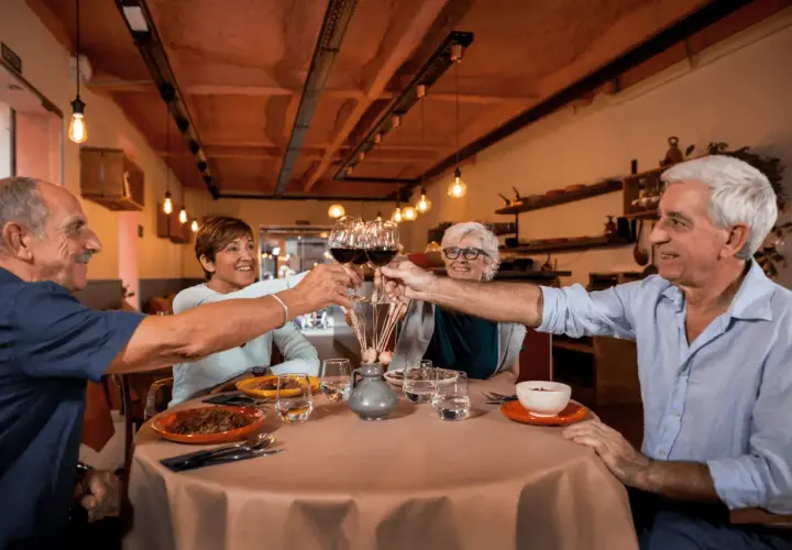 Cztery osoby wznoszą toast kieliszkami wina, tworząc radosny efekt cocktail party.