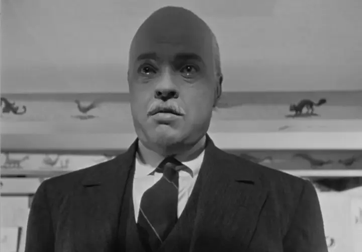 Orson Welles w jednym ze swoich filmów, z charakterystycznym wąsem i łysą głową, wygląda jakby miał do opowiedzenia mroczną historię.