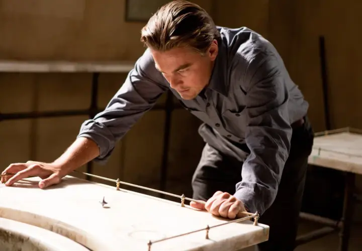 Leonardo DiCaprio pochyla się nad stołem, obserwując wirujący bączek. Czy to jego sposób na zrozumienie, czym jest incepcja?