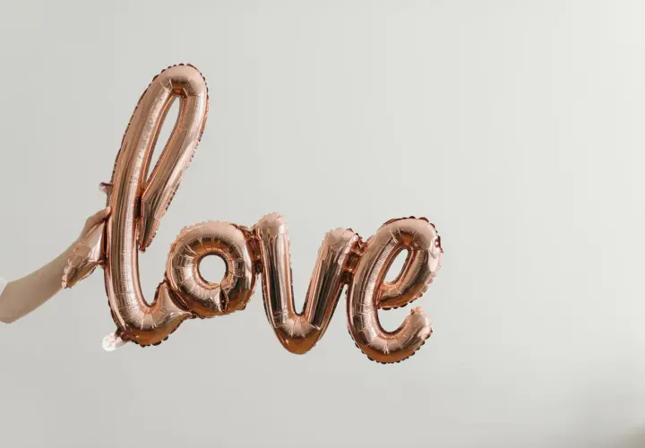 Różowe balony w kształcie napisu "love" unoszą się w powietrzu, tworząc piękną definicję miłości.
