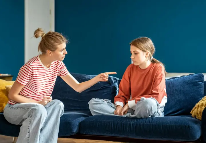 Matka z wyrzutem wskazuje palcem na córkę, która siedzi z opuszczoną głową. Scena sugeruje odrzucenie matki przez dorosłe dziecko.