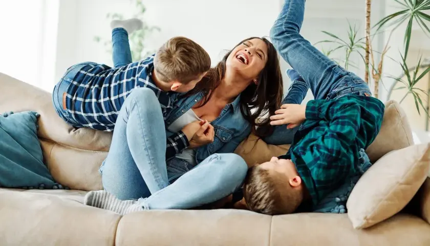 Szczęśliwa matka śmieje się, gdy jej synowie wspinają się na nią jak na partnera do zabawy.