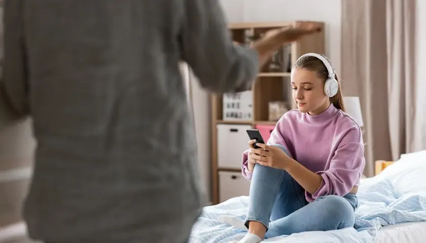 Nastoletnia córka mnie nie szanuje, siedzi na łóżku w słuchawkach, ignorując rodzica.