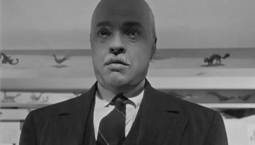 Orson Welles w jednym ze swoich filmów, z charakterystycznym wąsem i łysą głową, wygląda jakby miał do opowiedzenia mroczną historię.