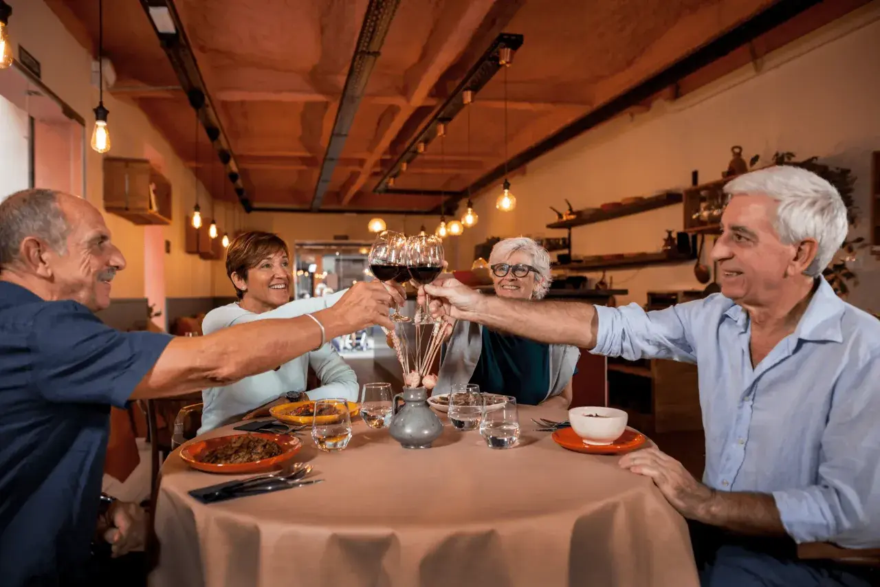 Cztery osoby wznoszą toast kieliszkami wina, tworząc radosny efekt cocktail party.
