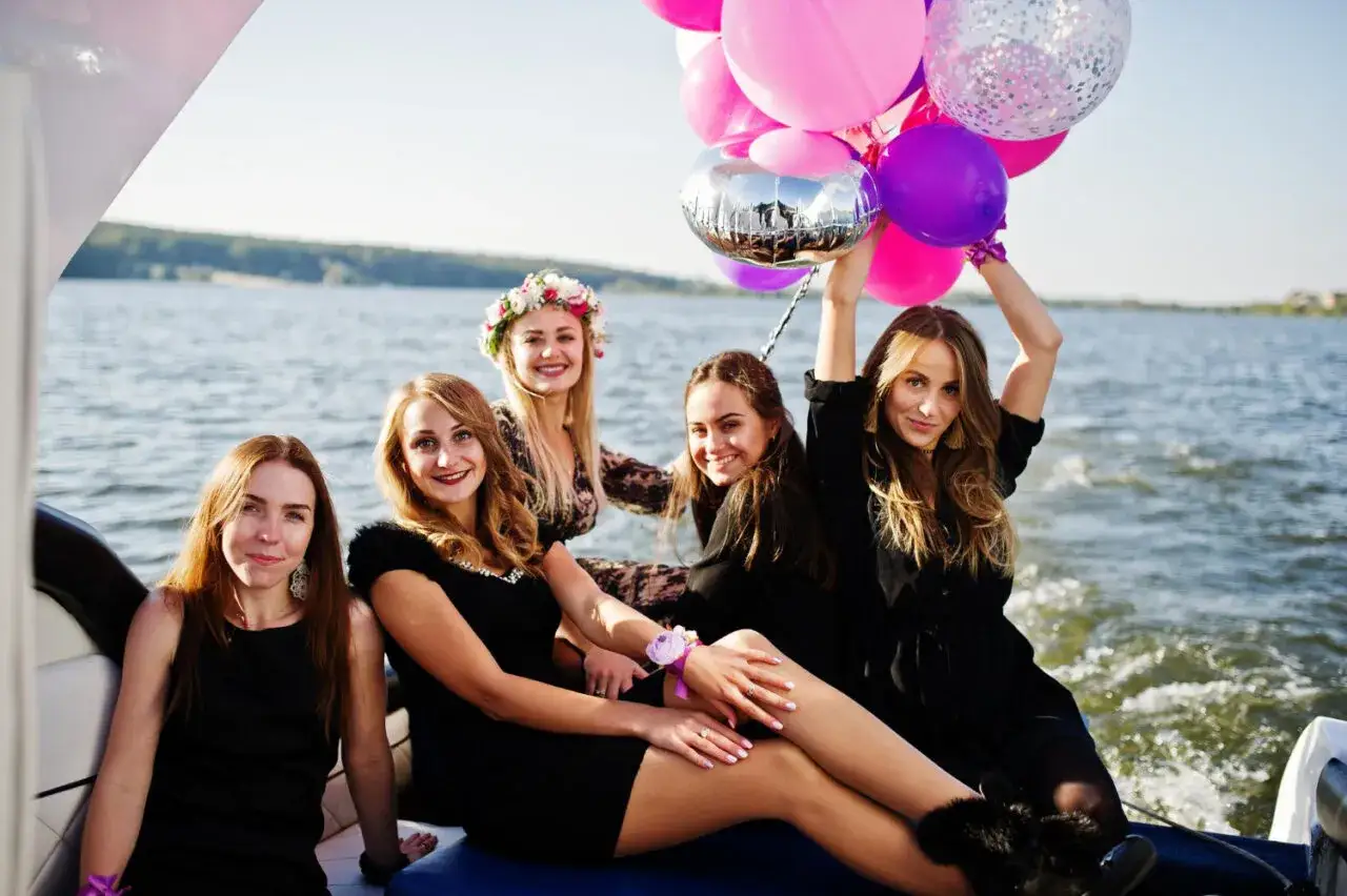 Uśmiechnięte kobiety na łodzi z balonami, świętujące wiecz&oacute;r panieński.